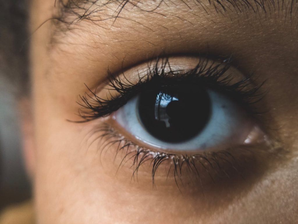 Detailed macro shot of a human eye with long eyelashes, highlighting texture and color.