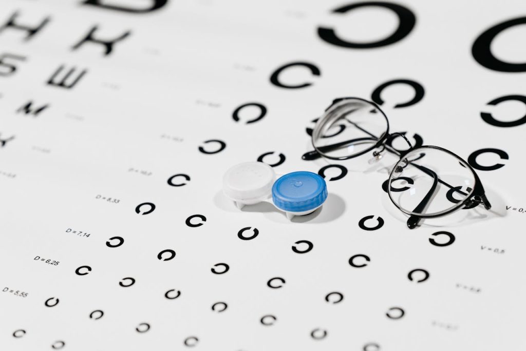 Close-up of contact lens case and eyeglasses on an eye test chart, ideal for vision care concepts.